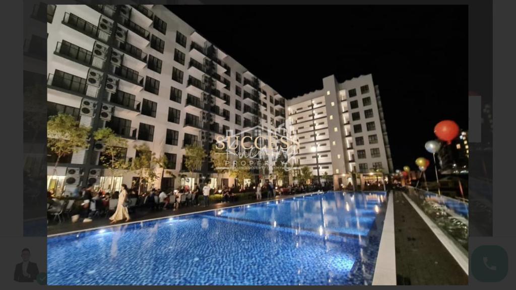 a large swimming pool in front of buildings at night at Armadale Residence-Gala City in Kuching