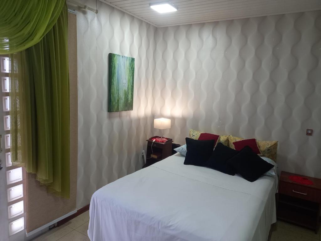 Un dormitorio con una cama blanca y una pintura verde en Estúdio central PG1 prox Paladium en Ponta Grossa