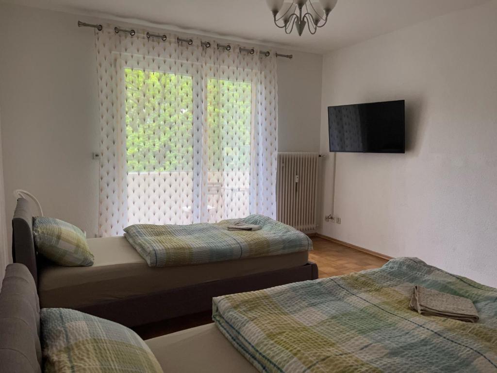 a bedroom with two beds and a tv and a window at Esslingen-Hegensberg Hegensbergerstrasse 22 in Oberesslingen