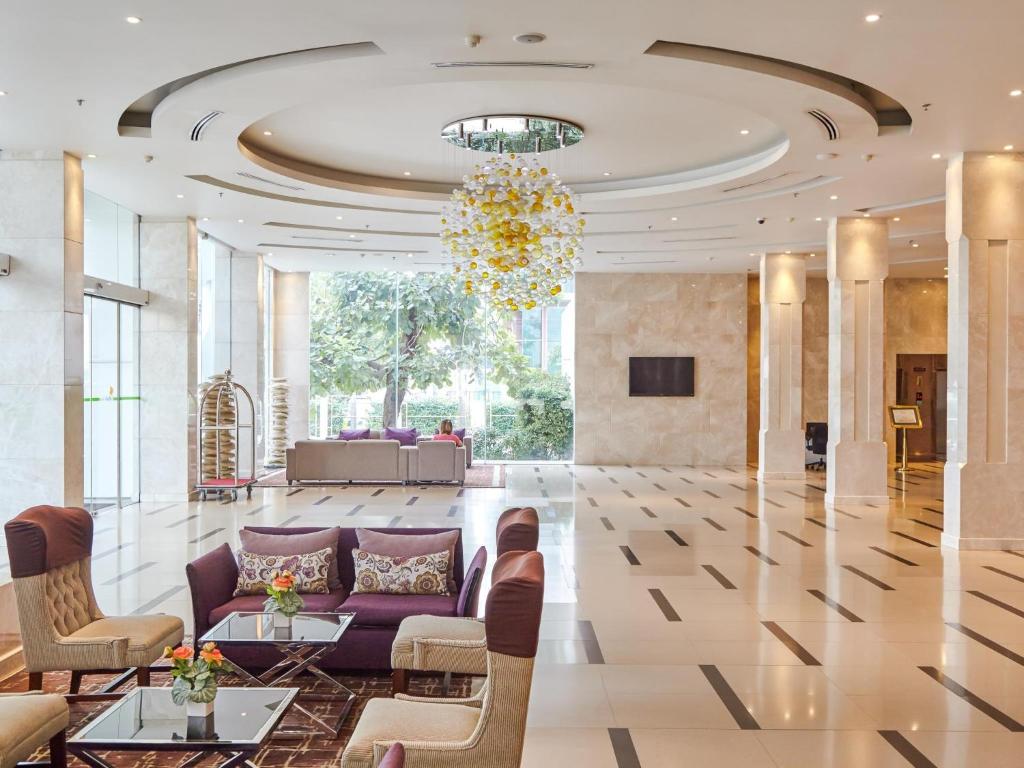 a lobby with a purple couch and chairs and a chandelier at Maple Hotel in Bangkok