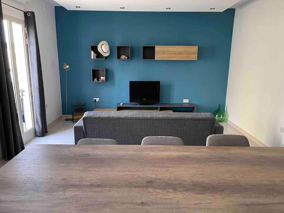 a living room with a couch and a blue wall at Sunset Apt Modern 1 bedroom Apt near the Beach in Birżebbuġa