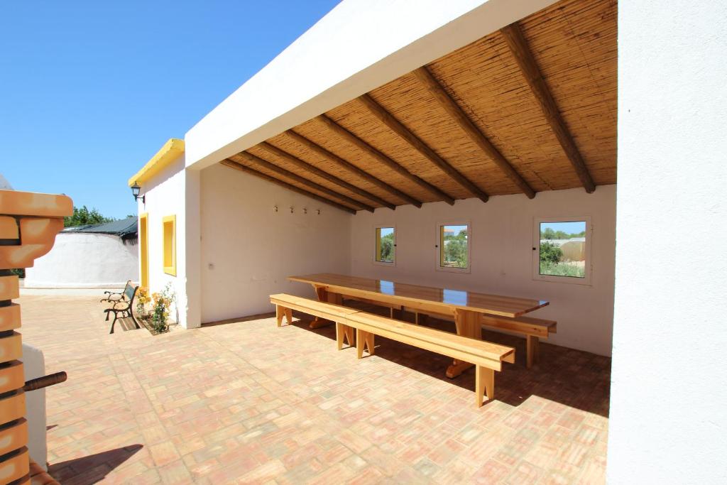 a pavilion with wooden benches on a brick patio at Vale da Rosa Cottage in Estói