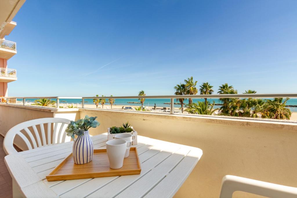 een tafel op een balkon met uitzicht op het strand bij Appartamento Bellariva A1 - MyHo Casa in Porto San Giorgio