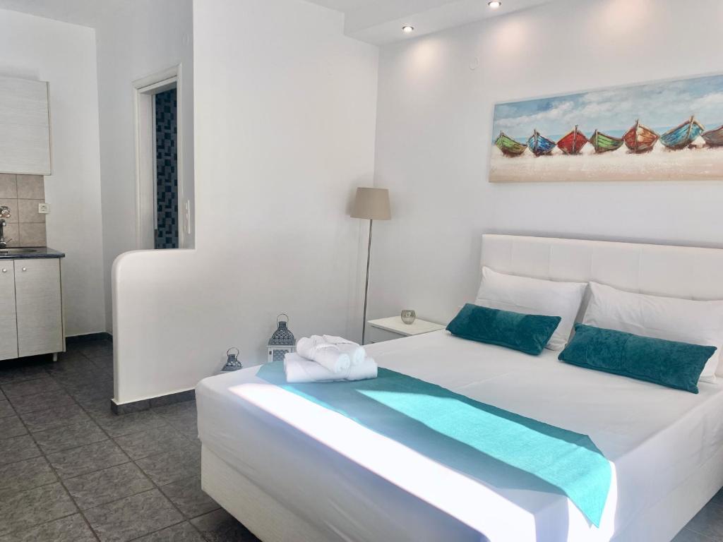- une chambre blanche avec un grand lit blanc et des oreillers bleus dans l'établissement Anemos Studios, à Adamas