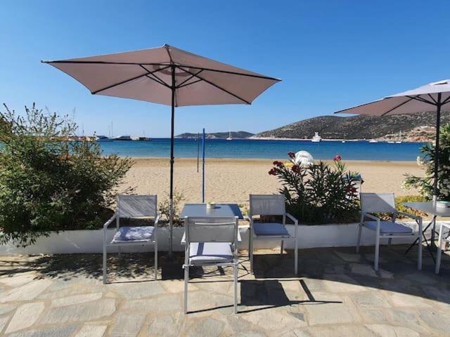 una mesa y sillas con sombrilla en la playa en Merope seaside house, en Platis Yialos Sifnos