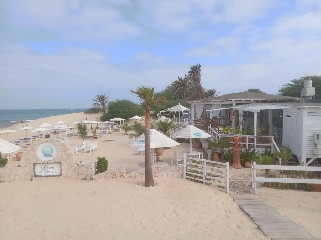 ein Strand mit Stühlen und Sonnenschirmen sowie ein Gebäude in der Unterkunft Útulný apartmán na Praia de Chaves, Boa Vista in Sal Rei