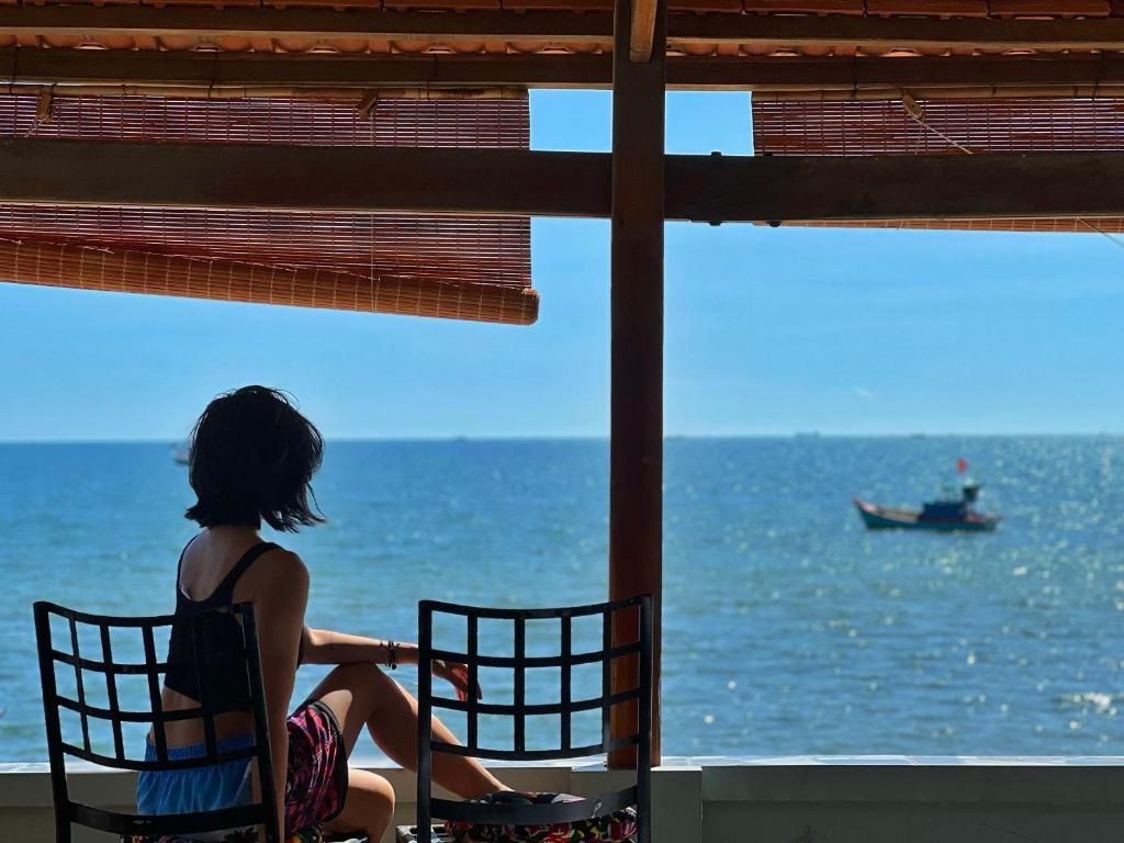 una mujer sentada en una silla mirando hacia el océano en Cocal Home Phu Quoc Fishing Village, en Phu Quoc
