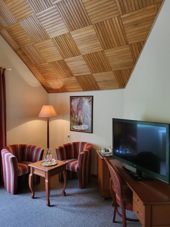a living room with two chairs and a flat screen tv at Vila Florena in Palanga
