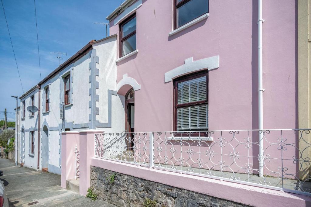 uma casa rosa e branca com uma cerca em Canol Y Bryn - 3 Bedroom Holiday Home - Tenby em Tenby