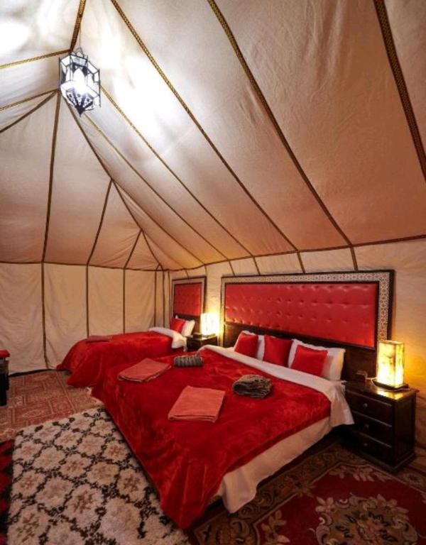una camera con letto rosso in tenda di Luxury Local Camp a Merzouga