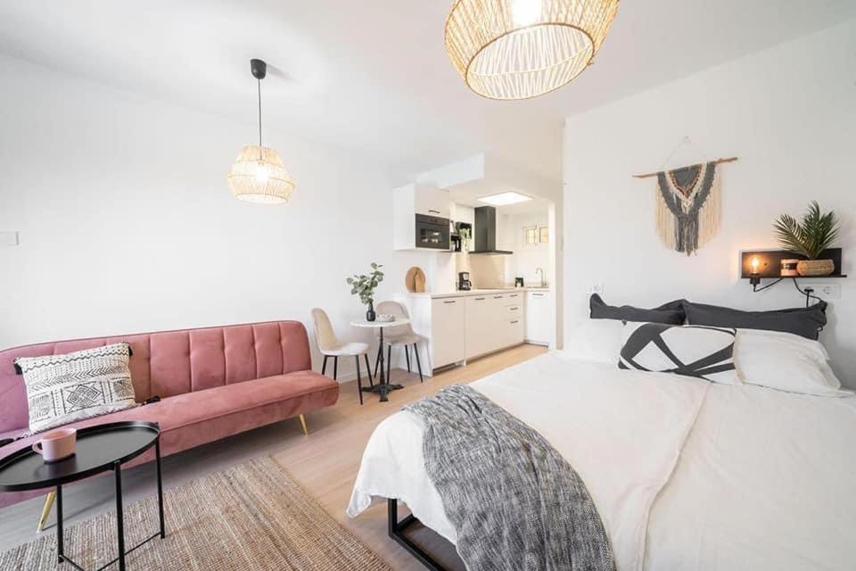 ein weißes Schlafzimmer mit einem rosa Sofa und einem Tisch in der Unterkunft Benalmadena Jupiter Sunsea View Apartments in Benalmádena