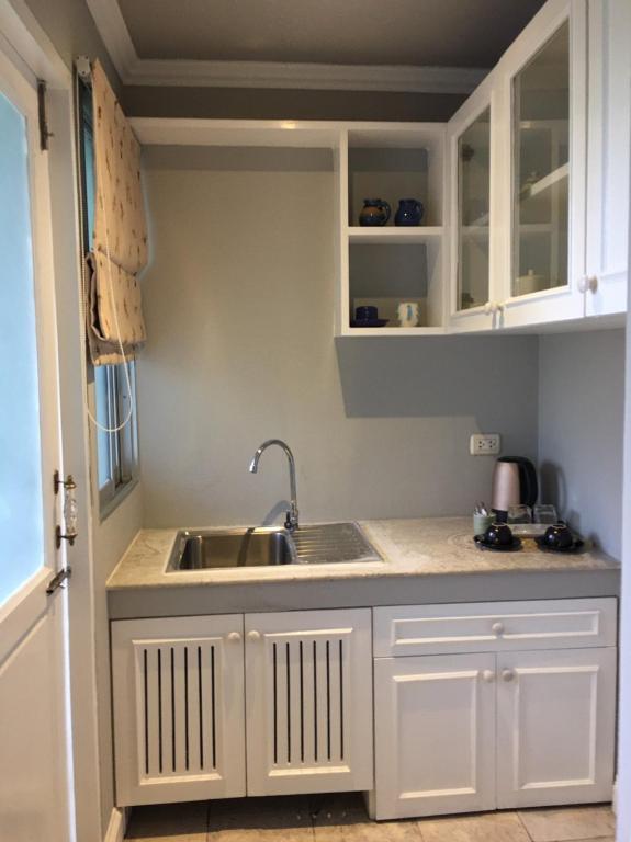A compact kitchenette with a sink, cabinets, kettle, and coffee equipment.