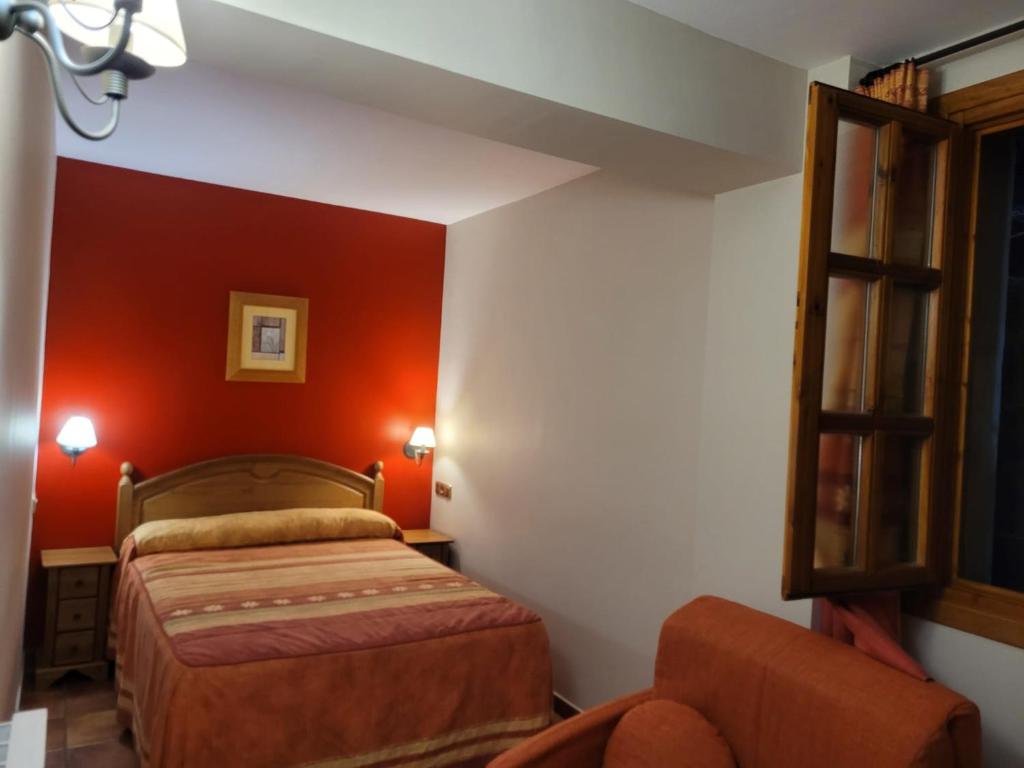 sypialnia z czerwonymi ścianami, łóżkiem i krzesłem w obiekcie Apartamentos Casa Español w mieście Broto