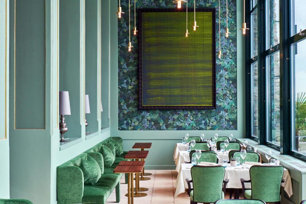 a dining room with white tables and green chairs at Château Gütsch in Luzern