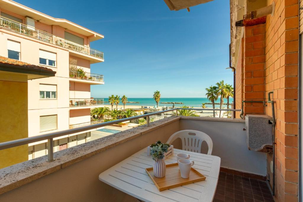 een balkon met een tafel en uitzicht op het strand bij Appartamento Bellariva B1-MyHo Casa in Porto San Giorgio