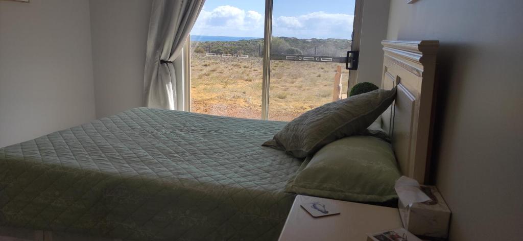 um quarto com uma cama e uma janela grande em Ocean Views Home Stay em Greenough