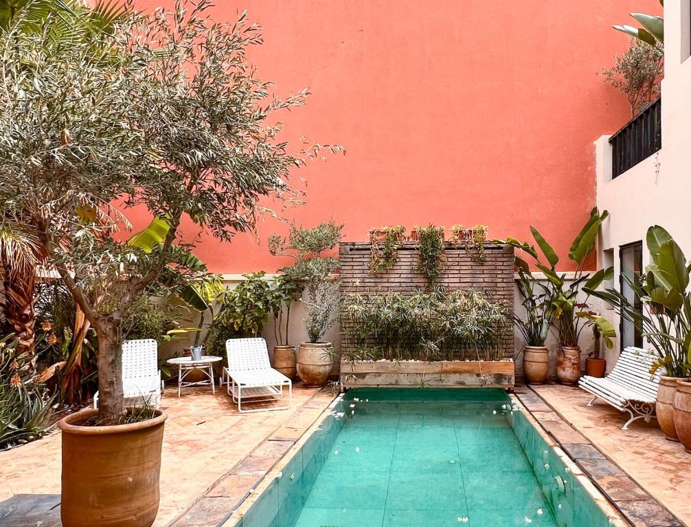 una piscina en un patio con sillas y un edificio en L'Annexe-Villa patio arboré & piscine privée, en Marrakech