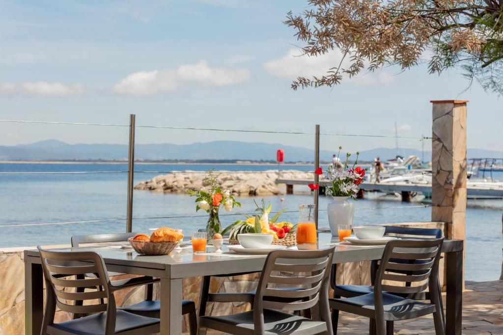 une table avec des chaises et une table avec vue sur l'eau dans l'établissement Le Cigalou, authentique cabanon de pêcheur en bord de mer avec sa terrasse spacieuse et aménagée, à Hyères