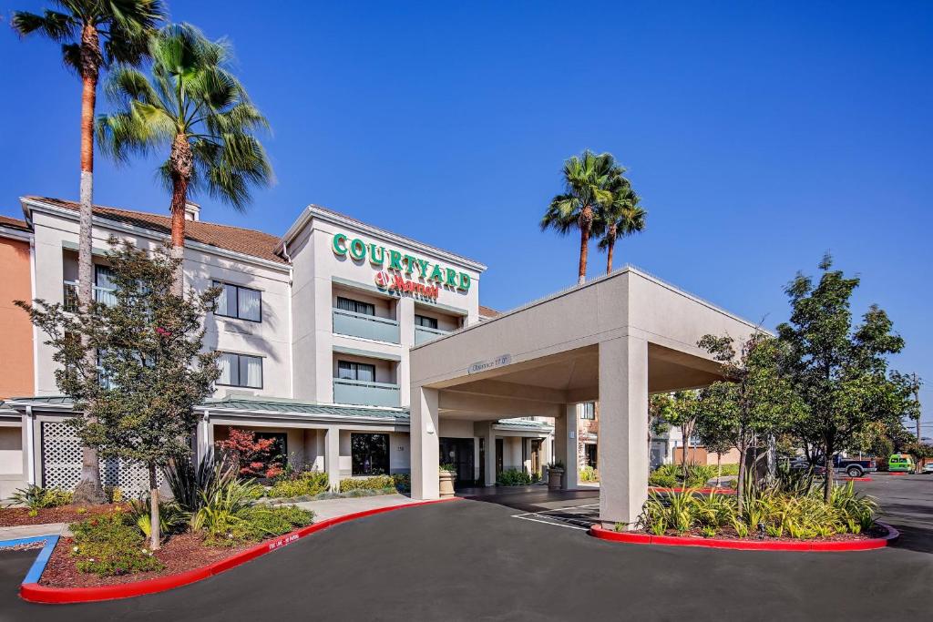 a hotel with palm trees in front of a building at Courtyard by Marriott Oakland Airport in Oakland