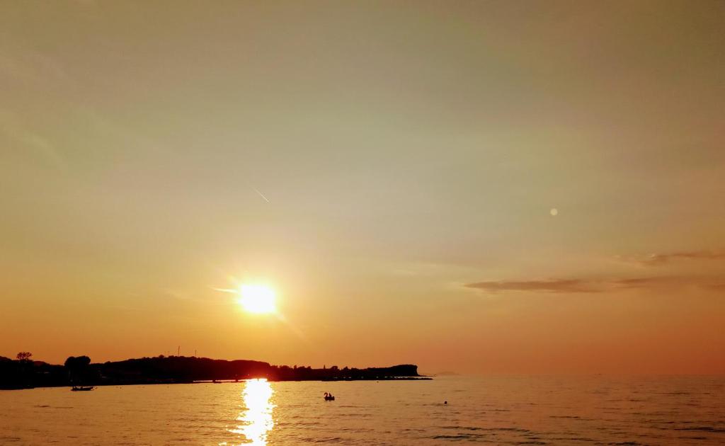 een zonsondergang boven het water met de zon in de lucht bij Nikos Seaside Apartments in (( Litherés ))