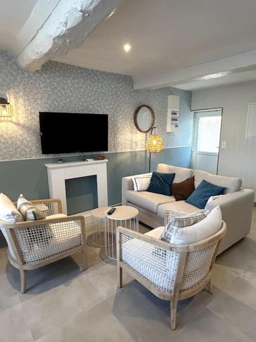 - un salon avec un canapé, des chaises et une télévision dans l'établissement Neptune - SILS, à Douvres-la-Délivrande