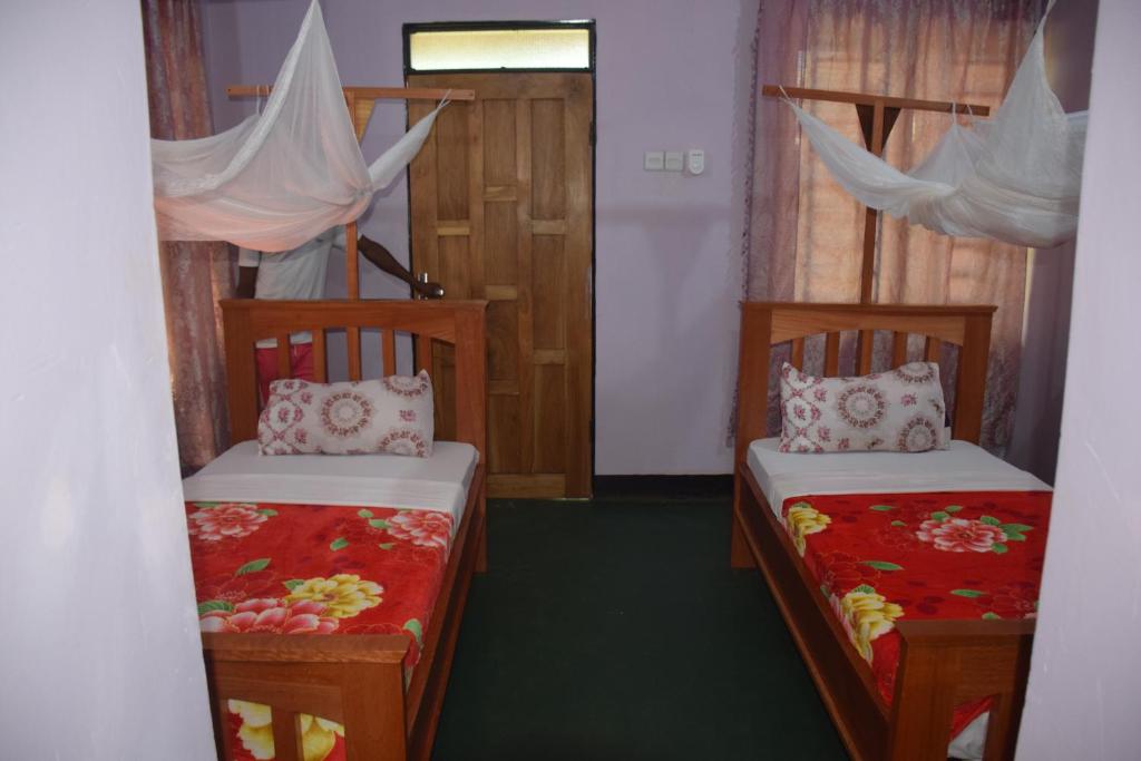 a room with two beds and a door with curtains at Kili View Lodge in Moshi