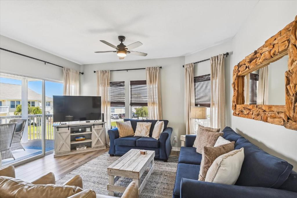 uma sala de estar com um sofá azul e uma televisão em Sandpiper Cove 9232 condo em Destin