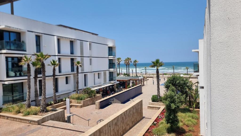- un bâtiment sur la plage avec des palmiers et l'océan dans l'établissement Anfa Place, à Casablanca