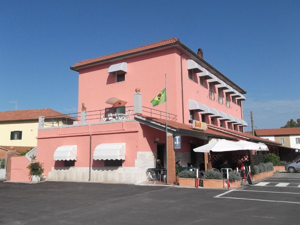a pink building with a flag on top of it at Hotel da Renato in Albinia