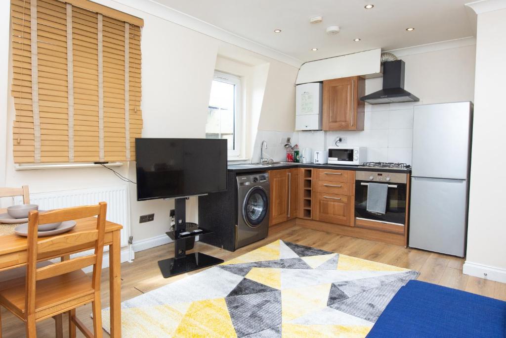 a kitchen with a refrigerator and a table and a stove at Evergreen Apartments-Flat 5, London in London