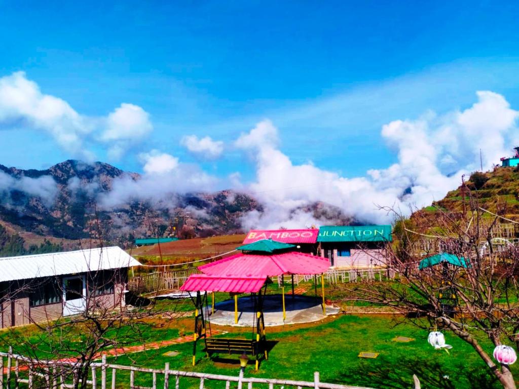 丹瑙提的住宿－Bamboo Junction Resort - Kanatal, Valley & Mountain View，山丘上一座带粉红色伞的建筑