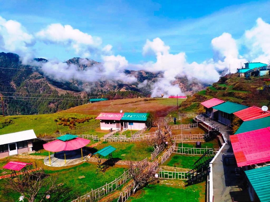 a village on top of a hill with colorful roofs at Bamboo Junction Resort - Kanatal, Valley & Mountain View in Dhanaulti
