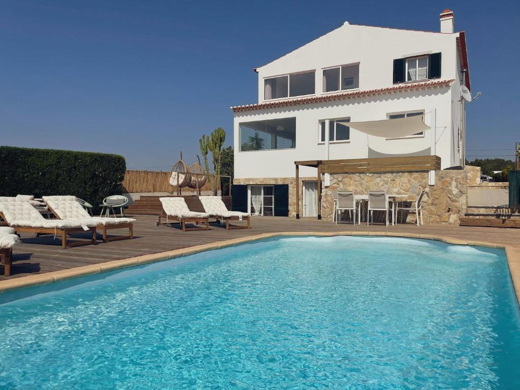 a villa with a swimming pool in front of a house at The Lighthouse Hostel Arrifana in Aljezur