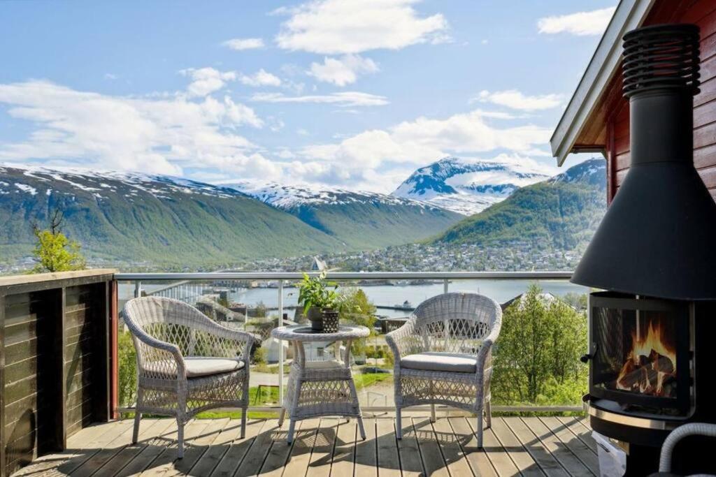 a balcony with chairs and a fireplace and mountains at Sea & Mountain View Apartment Tromsø in Tromsø