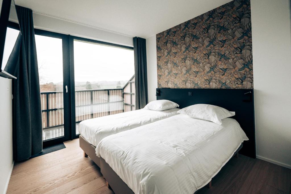 Duas camas num quarto com uma janela grande em Clos Nestor em Malmedy