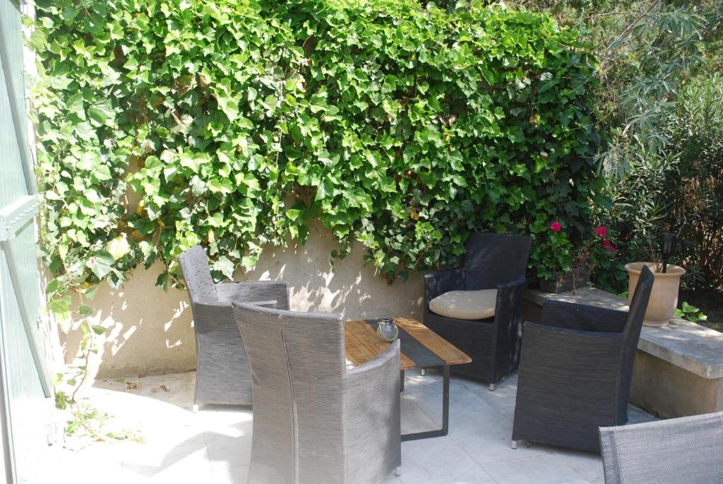 a patio with chairs and a table and a hedge at Casa del Sol in Arles