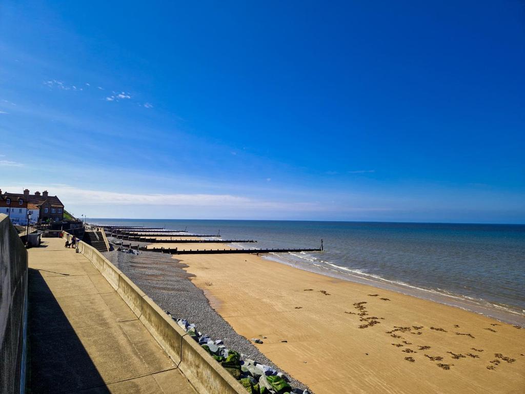 a beach with a pier and the ocean at The Wave - 3 bed beach front home in Sheringham in Sheringham