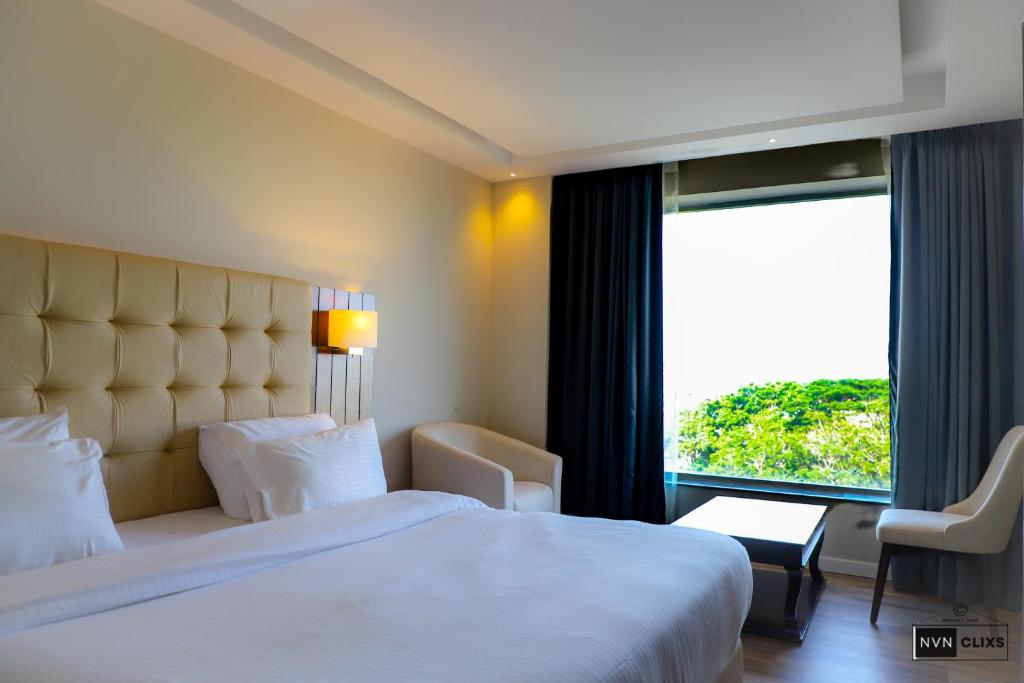 um quarto com uma cama grande e uma janela grande em Hotel The Sea View, Mangalore em Mangalore