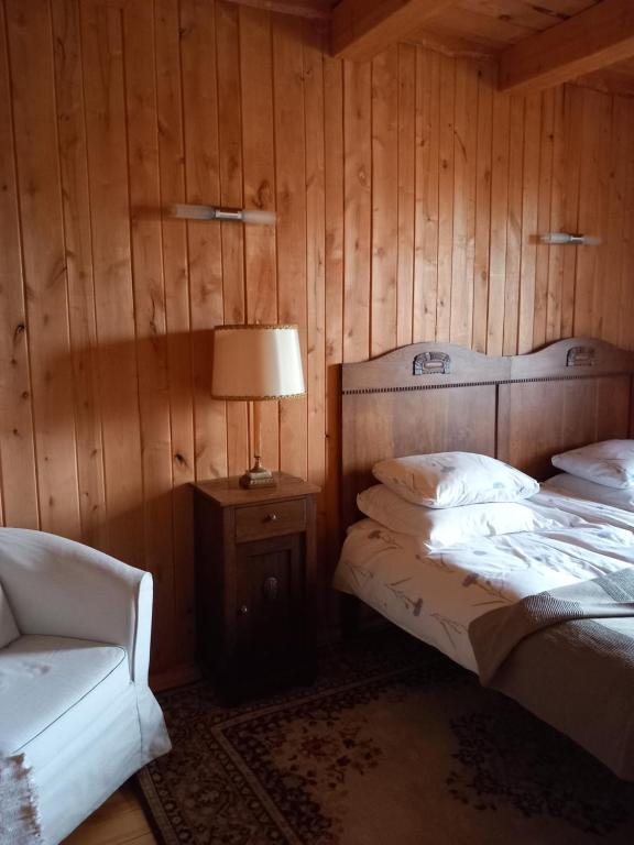 a bedroom with two beds and a lamp and a chair at Kaimo sodyba Senas rublis in Pesčiai