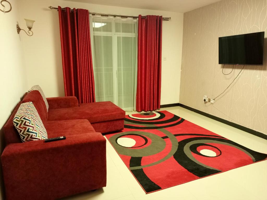 a living room with a red couch and a carpet at Casa Tranquilla - JKIA in Nairobi