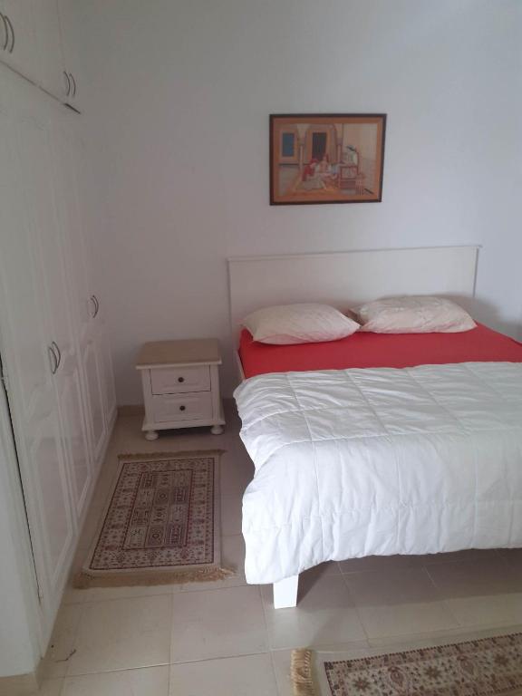 een kleine slaapkamer met een bed en een nachtkastje bij Appartement parfait pour les couples, bien équipé, à Hammamet centre 200m de la plage in Hammamet