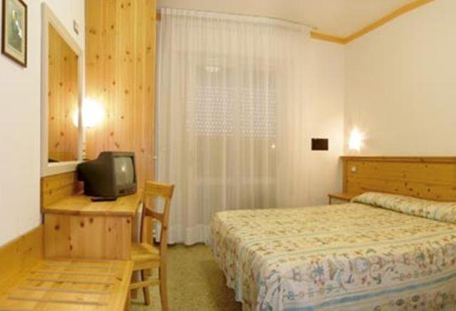 a bedroom with a bed and a desk with a television at Hotel Nelson in Lido di Jesolo