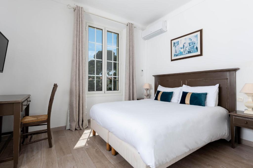 a bedroom with a bed and a desk and a window at Hôtel Beau Site - Cap d'Antibes in Antibes