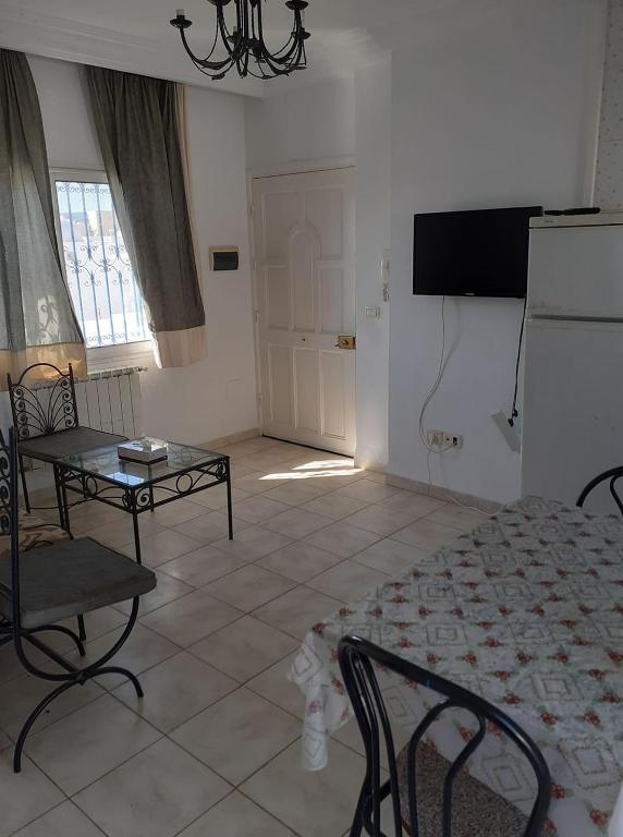 ein Wohnzimmer mit einem Bett, einem Tisch und einem TV in der Unterkunft Appartement S2 bien équipé à Hammamet centre (200m de la plage) in Hammamet