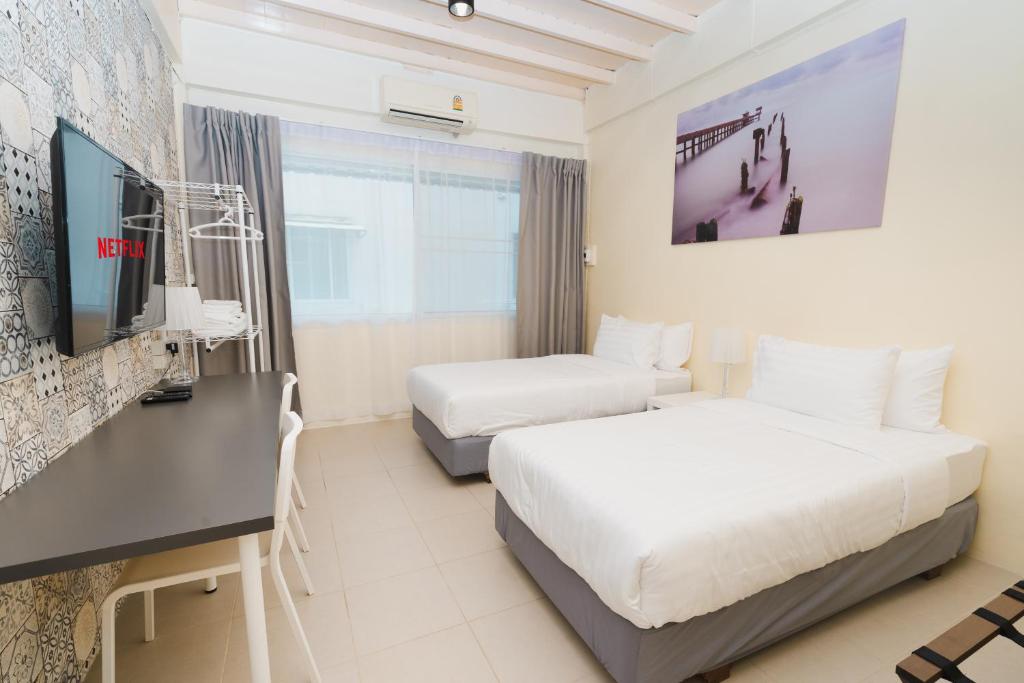 Habitación de hotel con 2 camas, escritorio y TV. en Spacious&Convenient_3BR/2BT_townhm for group stay en Bangkok
