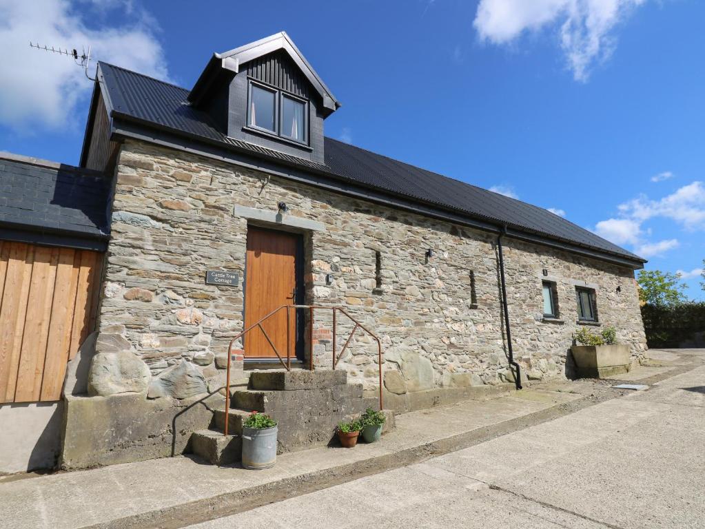 a stone building with a wooden door and stairs at Cattle Tree Cottage in Cardigan