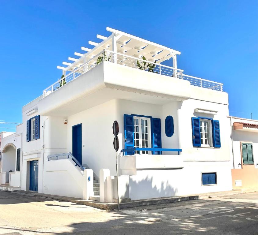 a white house with blue shutters and a balcony at Villa Azzurra in Marina di Mancaversa