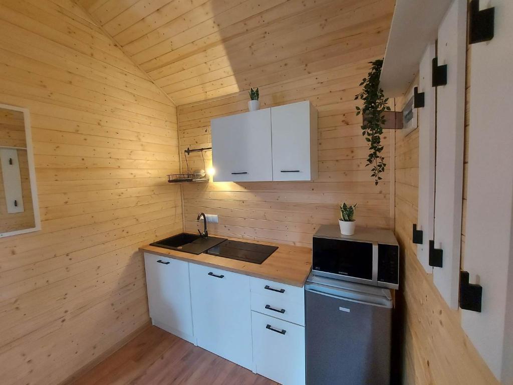 a small kitchen with white cabinets and a stove at Chatka pod orzechem in Spytkowice