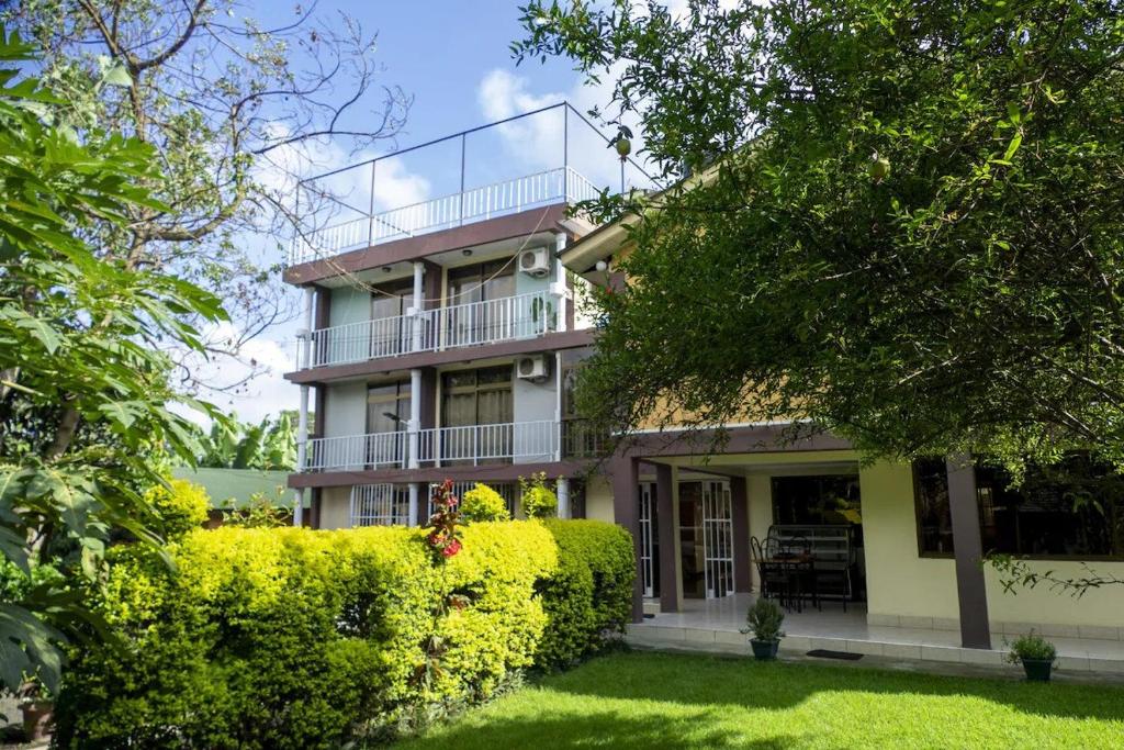 a large house with a balcony and bushes at Runako Lodge in Arusha