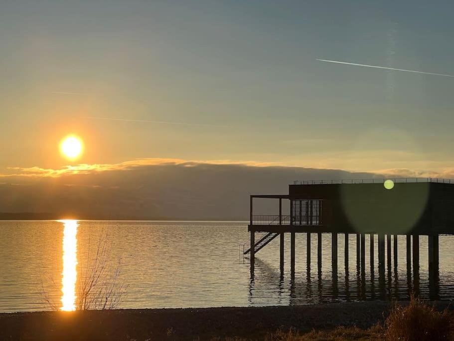 a pier with the sun setting over a body of water at Bodensee Loft in Strandnähe in Lochau
